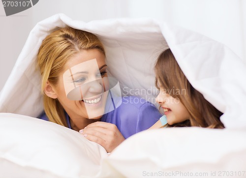 Image of mother and little girl under blanket at home