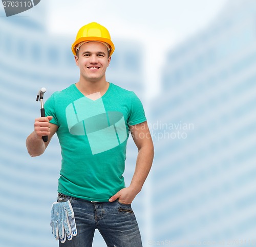 Image of smiling manual worker in helmet with hammer