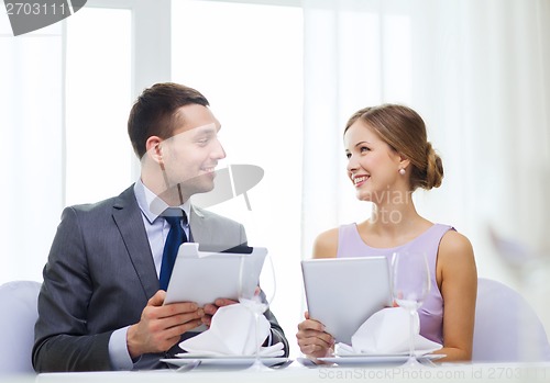 Image of couple with menus on tablet pc at restaurant