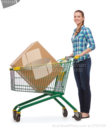 Image of smiling young woman with shopping cart and big box