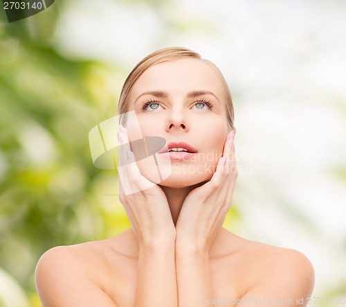 Image of beautiful woman touching her face and looking up