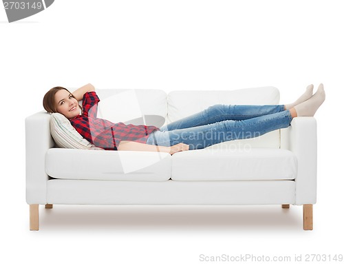 Image of smiling teenage girl lying on sofa