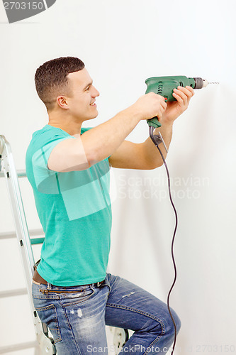 Image of man with electric drill making hole in wall