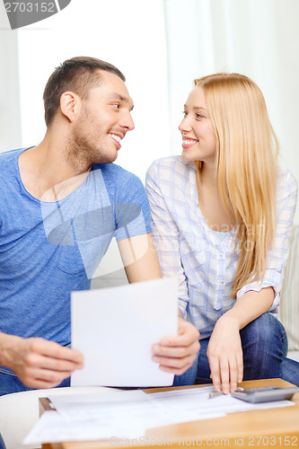 Image of smiling couple with papers and calculator at home