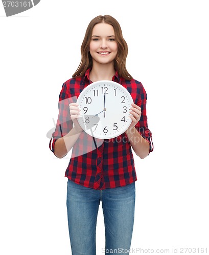 Image of young woman in casual clothes with wall clock