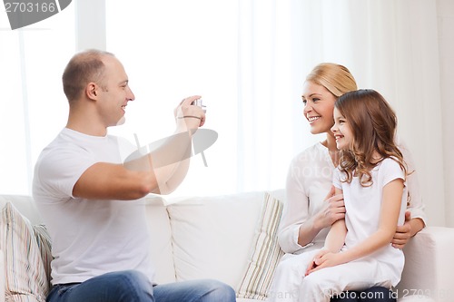 Image of happy father taking picture of mother and daughter