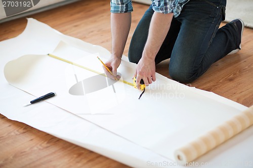 Image of close up of male hands measuring wallpaper