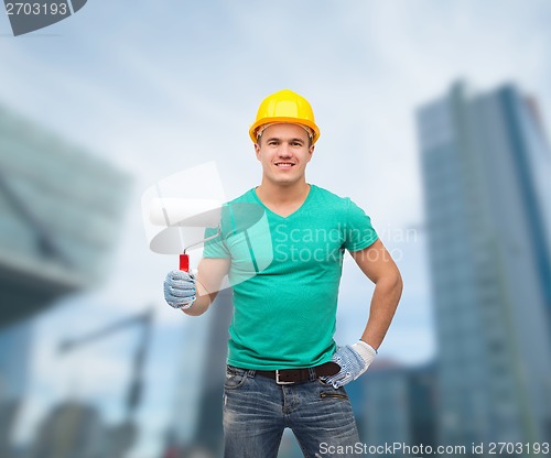 Image of smiling manual worker in helmet with paint roller