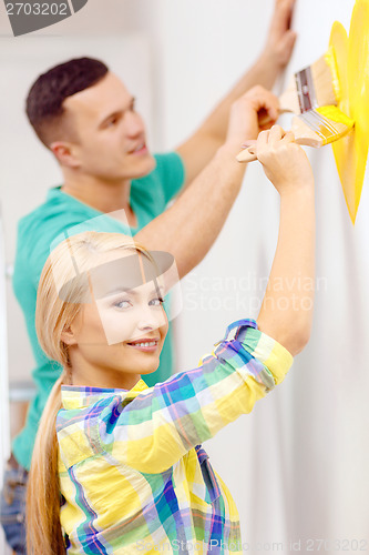 Image of smiling couple painting small heart on wall