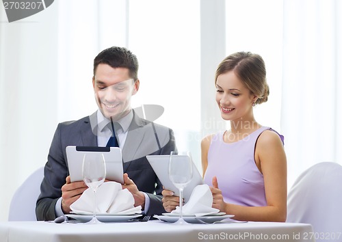 Image of couple with menus on tablet pc at restaurant