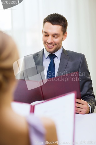 Image of smiling young man looking at menu at restaurant