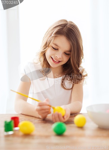 Image of smiling little girl coloring eggs for easter