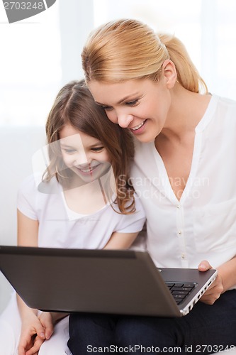 Image of smiling mother and little girl with laptop at home