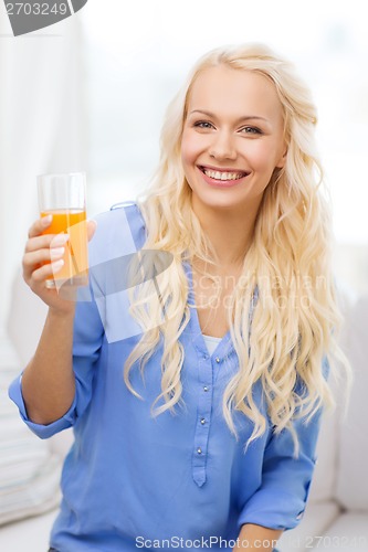 Image of smiling woman with glass of orange juice at home