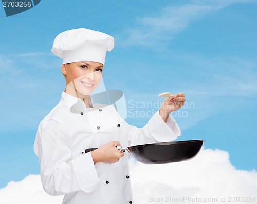 Image of smiling female chef with pan and spoon