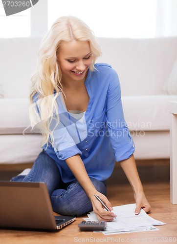 Image of smiling woman with papers, laptop and calculator