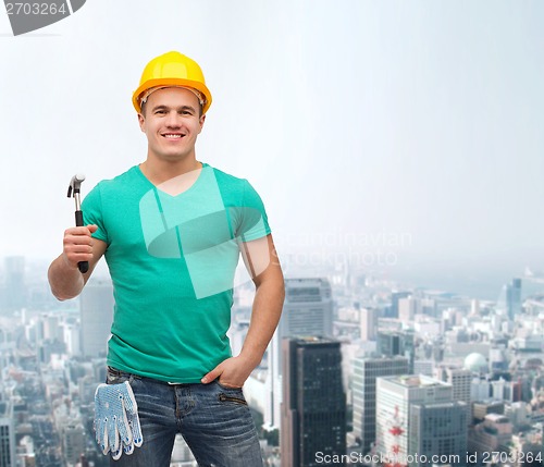 Image of smiling manual worker in helmet with hammer