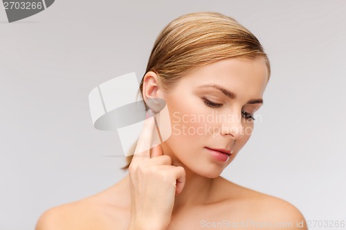 Image of calm woman touching her ear