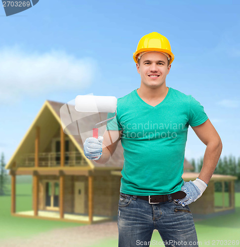 Image of smiling manual worker in helmet with paint roller