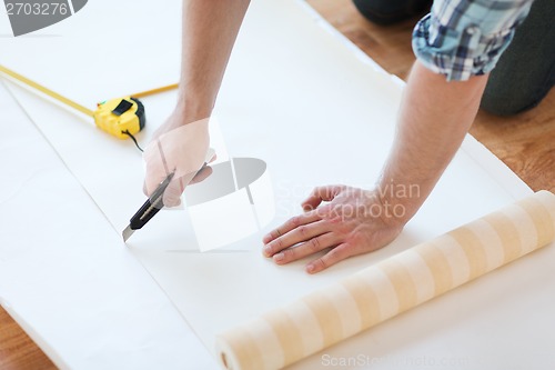 Image of close up of male hands cutting wallpaper