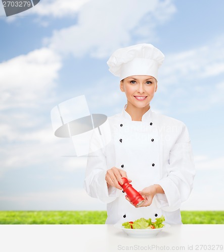 Image of smiling female chef with preparing salad