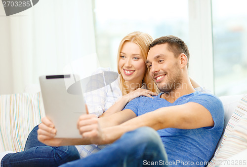 Image of smiling happy couple with tablet pc at home