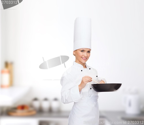 Image of smiling female chef with pan and spoon