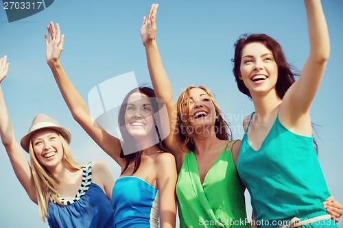 Image of girls walking on the beach and waivng hands