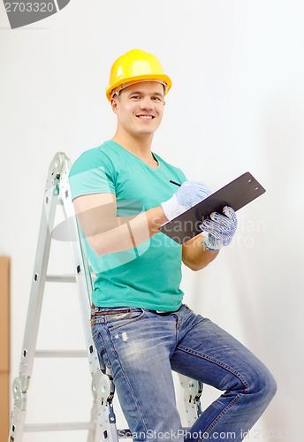 Image of smiling man in protective helmet with clipboard