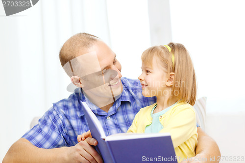 Image of smiling father and daughter with book at home