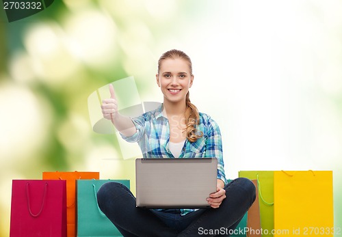 Image of smiling girl with laptop comuter and shopping bags