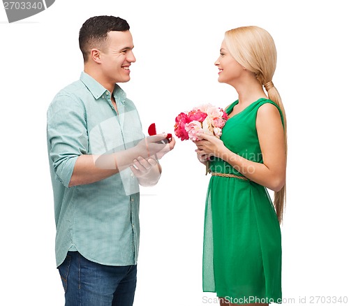 Image of smiling couple with flower bouquet and ring