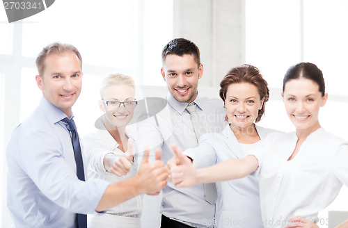 Image of business team showing thumbs up in office