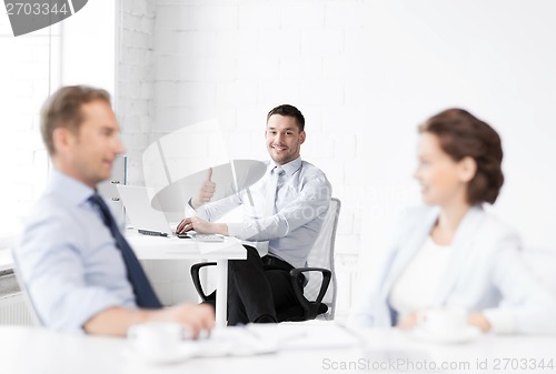 Image of happy businessman showing thumbs up in office