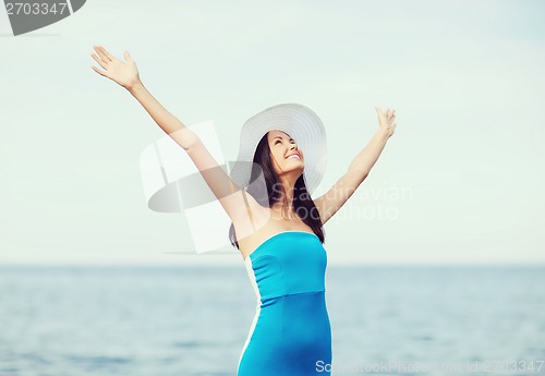 Image of girl with hands up on the beach