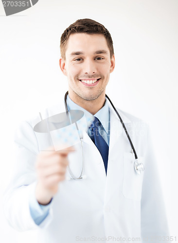 Image of young male doctor with pack of pills