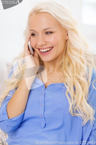 Image of smiling woman with smartphone at home