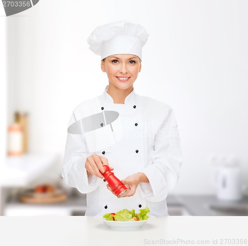 Image of smiling female chef with preparing salad