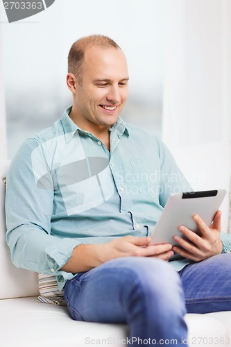 Image of smiling man working with tablet pc at home