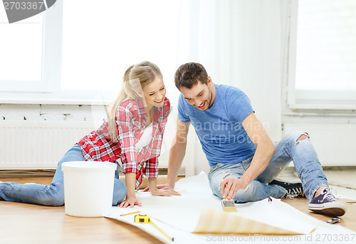 Image of smiling couple smearing wallpaper with glue