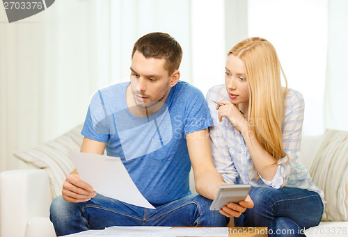 Image of busy couple with papers and calculator at home