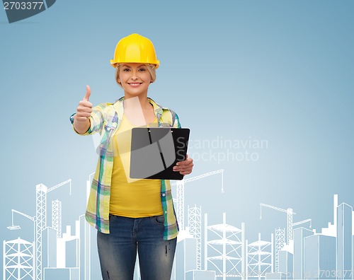 Image of smiling woman in helmet with clipboard