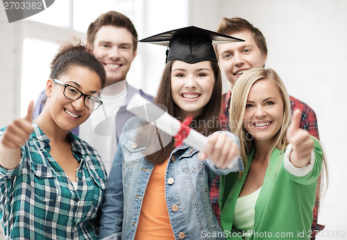 Image of girl in graduation cap with diploma and students