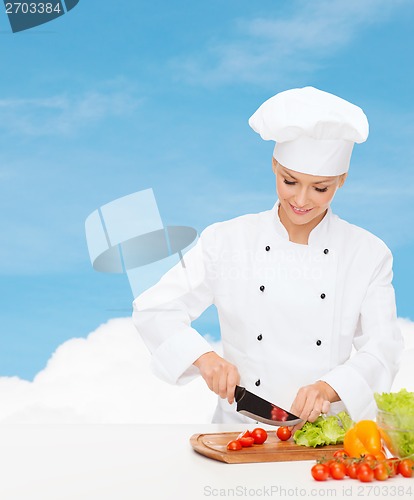Image of smiling female chef chopping vagetables