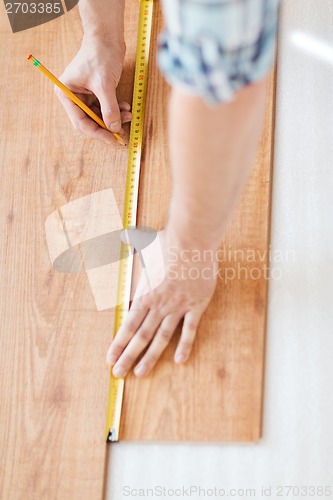 Image of close up of male hands measuring wood flooring