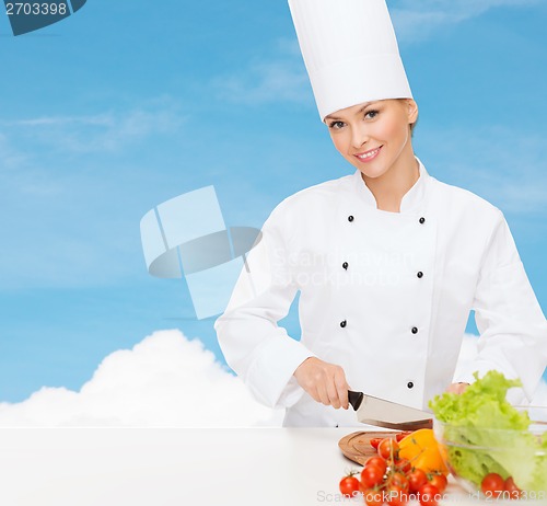 Image of smiling female chef chopping vagetables