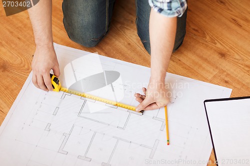 Image of close up of male hands measuring blueprint