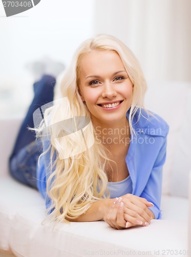 Image of smiling young woman lying on sofa at home