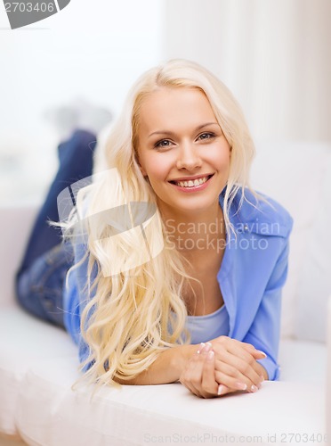 Image of smiling young woman lying on sofa at home