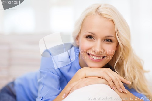 Image of smiling young woman lying on sofa at home